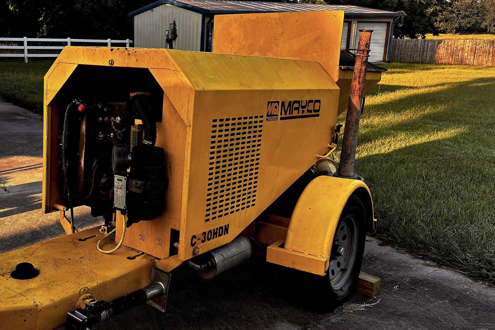 Engine and control panel of the Mayco concrete pump with the side cover open.